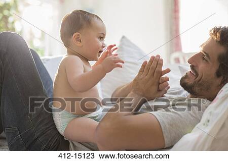 Father playing with baby boy on bed View Large Photo Image Stock Image - Father playing with baby boy on bed. Fotosearch