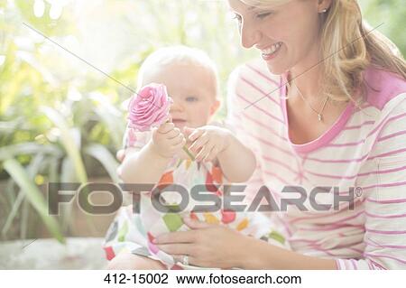 Mother and baby girl playing with flower View Large Photo Image Stock Image - Mother and baby girl playing with flower. Fotosearch
