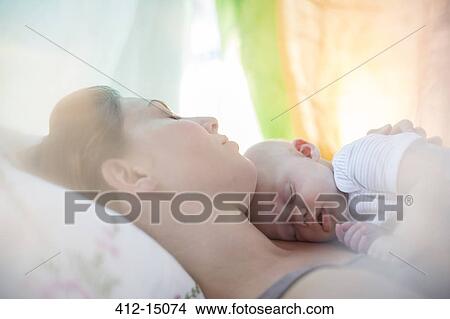 Mother and baby girl sleeping on bed View Large Photo Image Picture - Mother and baby girl sleeping on bed. Fotosearch