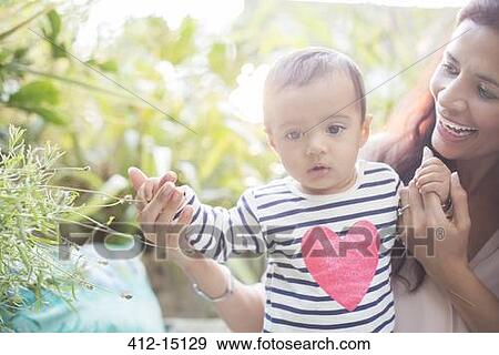 Stock Photo - Mother helping baby boy walk outdoors. Fotosearch