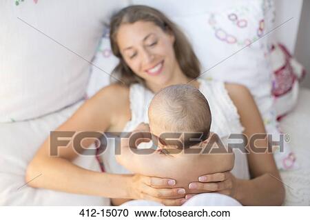 Mother holding baby boy on bed View Large Photo Image Stock Image - Mother holding baby boy on bed. Fotosearch