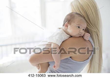 Stock Image - Mother holding baby girl in nursery. Fotosearch