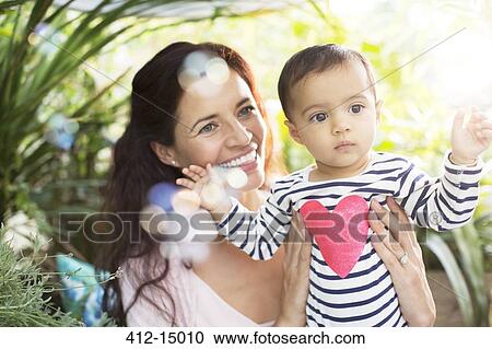 Stock Image - Mother holding baby girl outdoors. Fotosearch