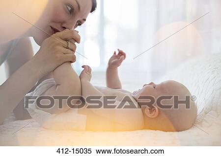Stock Photography - Mother kissing baby girl's feet. Fotosearch
