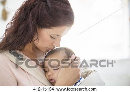 Picture - Mother kissing sleeping baby girl. Fotosearch