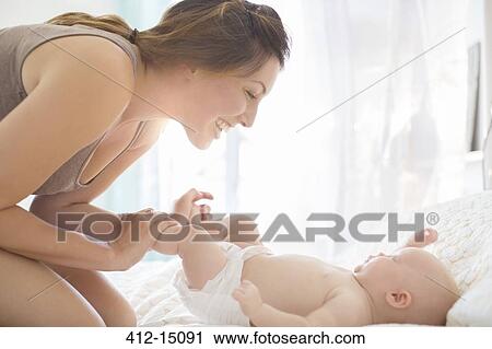 Mother playing with baby girl on bed View Large Photo Image Stock Image - Mother playing with baby girl on bed. Fotosearch
