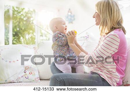 Mother playing with baby girl on sofa View Large Photo Image Stock Image - Mother playing with baby girl on sofa. Fotosearch