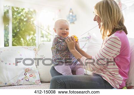 Mother playing with baby girl on sofa View Large Photo Image Stock Photo - Mother playing with baby girl on sofa. Fotosearch