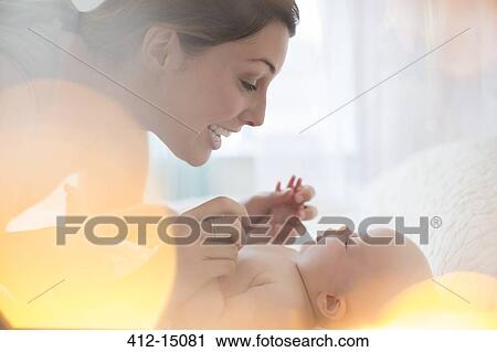 Stock Image - Mother playing with baby girl. Fotosearch