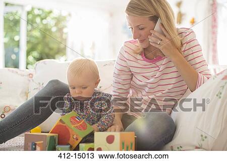 Stock Image - Mother with baby girl talking on cell phone. Fotosearch