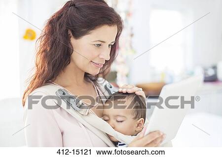 Mother with sleeping baby boy using digital tablet View Large Photo Image Stock Image - Mother with sleeping baby boy using digital tablet. Fotosearch