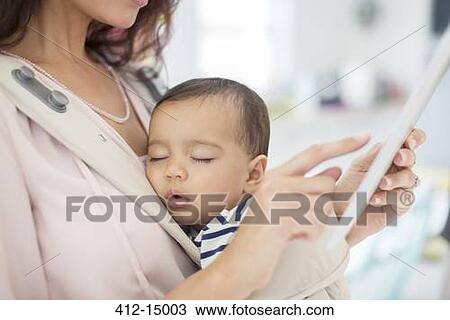 Mother with sleeping baby girl using digital tablet View Large Photo Image Stock Image - Mother with sleeping baby girl using digital tablet. Fotosearch