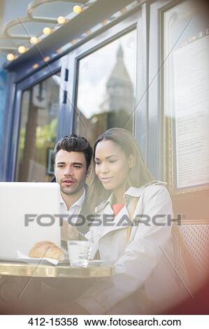 Stock Photo - Business people using laptop at sidewalk cafe. Fotosearch