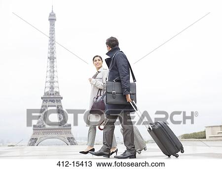 Stock Image - Business people with suitcases passing by Eiffel Tower, Paris, France. Fotosearch