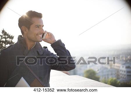Businessman on cell phone overlooking city View Large Photo Image Stock Image - Businessman on cell phone overlooking city. Fotosearch