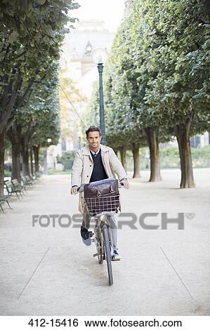Businessman riding bicycle in park, Paris, France View Large Photo Image Stock Photograph - Businessman riding bicycle in park, Paris, France. Fotosearch