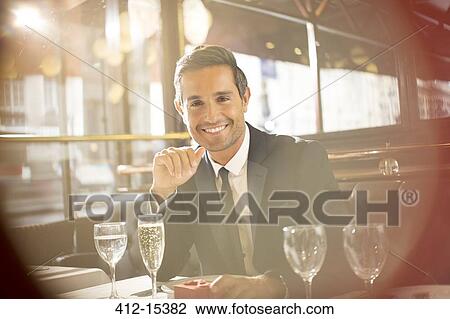 Stock Image - Businessman smiling at restaurant. Fotosearch