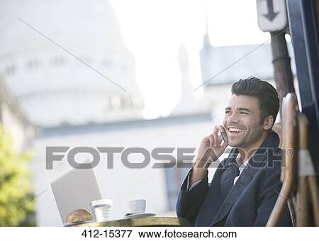 Stock Photo - Businessman talking on cell phone at sidewalk cafe near Sacre Coeur Basilica, Paris, France. Fotosearch