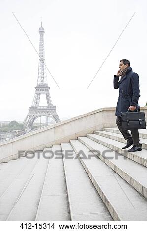 Picture - Businessman talking on cell phone on steps near Eiffel Tower, Paris, France. Fotosearch