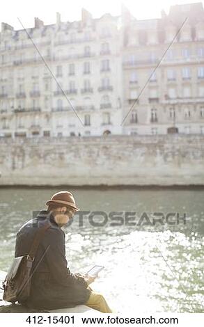 Stock Image - Businessman using cell phone along Seine River, Paris, France. Fotosearch
