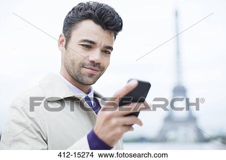 Picture - Businessman using cell phone by Eiffel Tower, Paris, France. Fotosearch