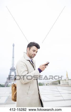 Stock Image - Businessman using cell phone by Eiffel Tower, Paris, France. Fotosearch
