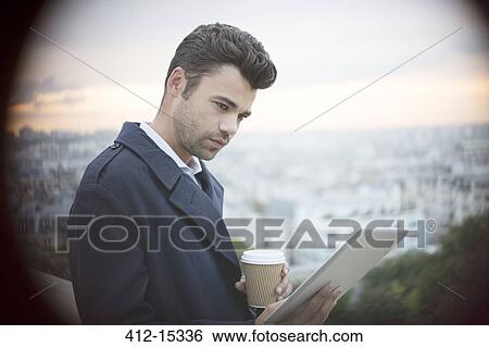 Businessman using digital tablet overlooking Paris, France View Large Photo Image Stock Photograph - Businessman using digital tablet overlooking Paris, France. Fotosearch