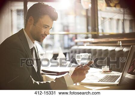 Stock Image - Businessman using laptop in restaurant. Fotosearch