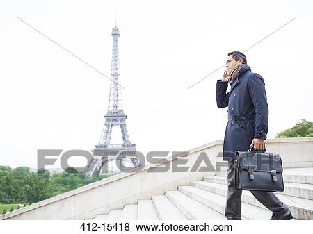 Stock Photo - Businessmen on cell phone on steps near Eiffel Tower, Paris, France. Fotosearch
