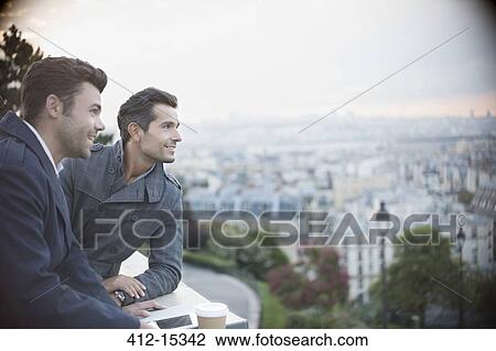 Stock Image - Businessmen overlooking cityscape, Paris, France. Fotosearch