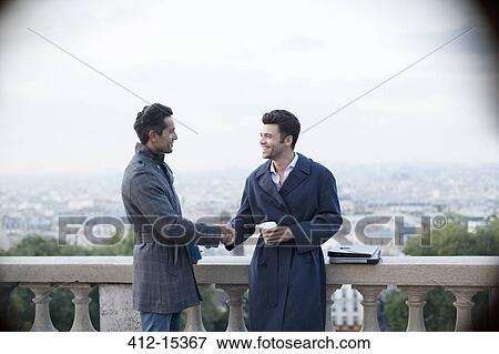 Businessmen shaking hands at railing overlooking Paris, France View Large Photo Image Stock Photo - Businessmen shaking hands at railing overlooking Paris, France. Fotosearch