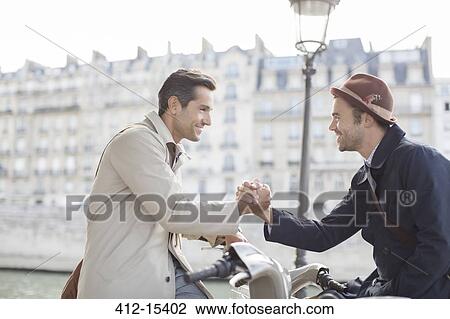 Businessmen shaking hands on bicycles along Seine River, Paris, France View Large Photo Image Stock Image - Businessmen shaking hands on bicycles along Seine River, Paris, France. Fotosearch