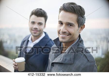 Businessmen smiling with city in background View Large Photo Image Stock Image - Businessmen smiling with city in background. Fotosearch