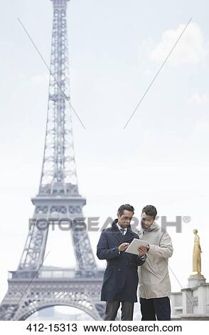 Stock Image - Businessmen using digital tablet by Eiffel Tower, Paris, France. Fotosearch