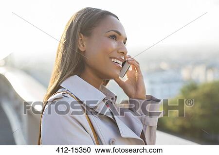 Stock Image - Businesswoman on cell phone outdoors. Fotosearch