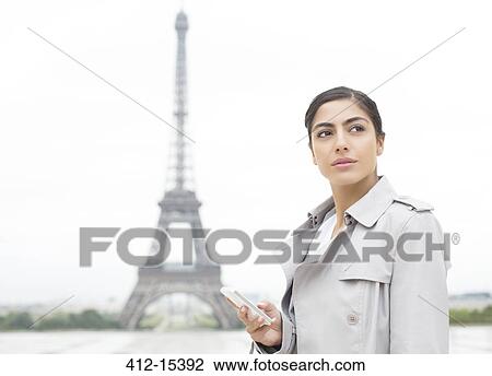 Stock Image - Businesswoman using cell phone near Eiffel Tower, Paris, France. Fotosearch