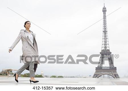 Stock Photo - Businesswoman walking past Eiffel Tower, Paris, France. Fotosearch