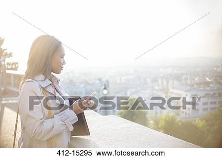 Stock Photography - Businesswoman with cell phone overlooking Paris, France. Fotosearch