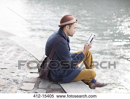 Man using digital tablet along river View Large Photo Image Stock Photography - Man using digital tablet along river. Fotosearch