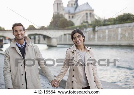 Picture - Couple holding hands along Seine River near Notre Dame Cathedral, Paris, France. Fotosearch