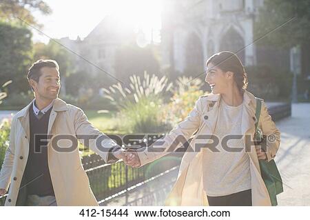 Couple holding hands in urban park View Large Photo Image Picture - Couple holding hands in urban park. Fotosearch