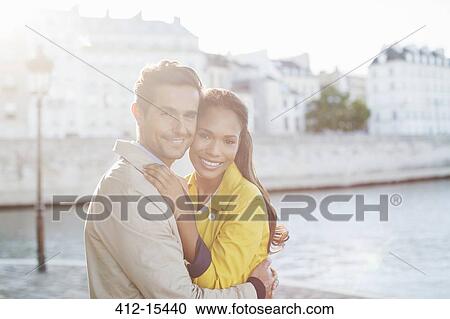 Stock Image - Couple hugging along Seine River, Paris, France. Fotosearch