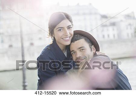 Stock Image - Couple hugging along Seine River, Paris, France. Fotosearch