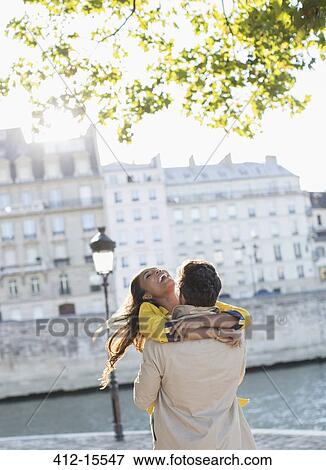 Stock Photo - Couple hugging along Seine River, Paris, France. Fotosearch
