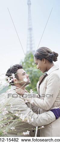 Stock Image - Couple hugging in front of Eiffel Tower, Paris, France. Fotosearch
