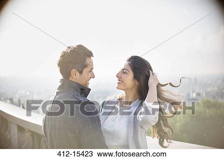 Stock Image - Couple hugging on urban balcony. Fotosearch