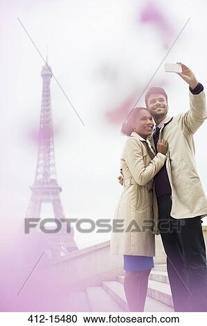 Couple taking self-portrait in front of Eiffel Tower, Paris, France View Large Photo Image Stock Image - Couple taking self-portrait in front of Eiffel Tower, Paris, France. Fotosearch