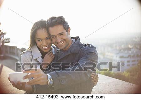 Couple taking self-portrait overlooking city View Large Photo Image Stock Image - Couple taking self-portrait overlooking city. Fotosearch