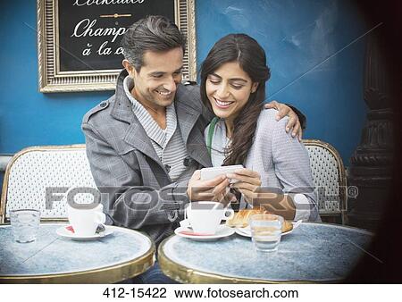 Couple using cell phone at sidewalk cafe, Paris, France View Large Photo Image Stock Image - Couple using cell phone at sidewalk cafe, Paris, France. Fotosearch