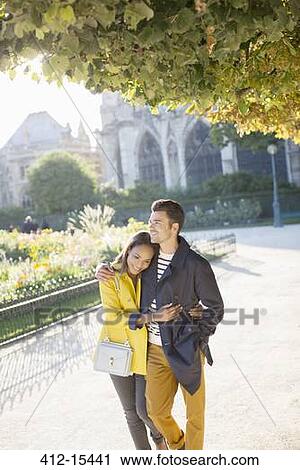 Stock Image - Couple walking together in urban park. Fotosearch